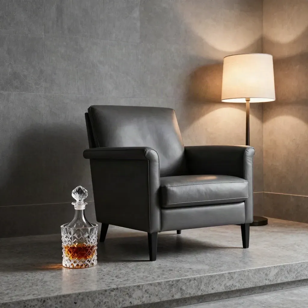 Poltrona in pelle, caraffa e lampada bassa davanti a una parete di pietra, luce radente.